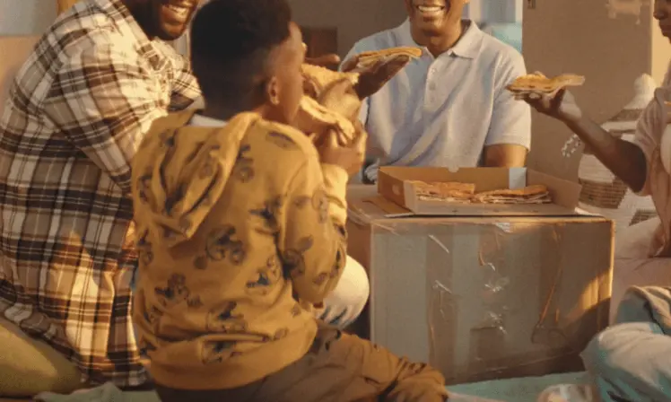 Family sharing a takeaway pizza on a packed moving box
