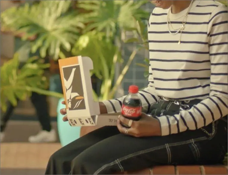 Seated person enjoying a pizza and coke`